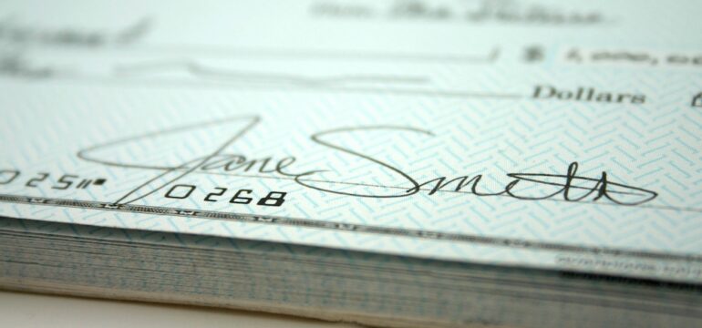 Paper check filled out completely with a clear signature to prevent check fraud.