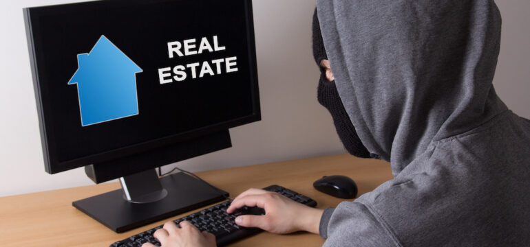 Cybercriminal committing home title theft. Photo of a thief in a mask searching for information about real estate online.